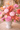 Bouquet of pink, orange, and white flowers in a white vase on a blurred background