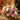 Bouquet of pink, white, and purple flowers in a decorative pot on a wooden surface.