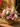 Bouquet of pink, white, and purple flowers in a decorative pot on a wooden surface.