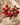 Bouquet of red and pink flowers in a white vase on a round stone surface with a beige wall background.