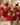 Bouquet of red roses and pink flowers in a vase on a textured surface.